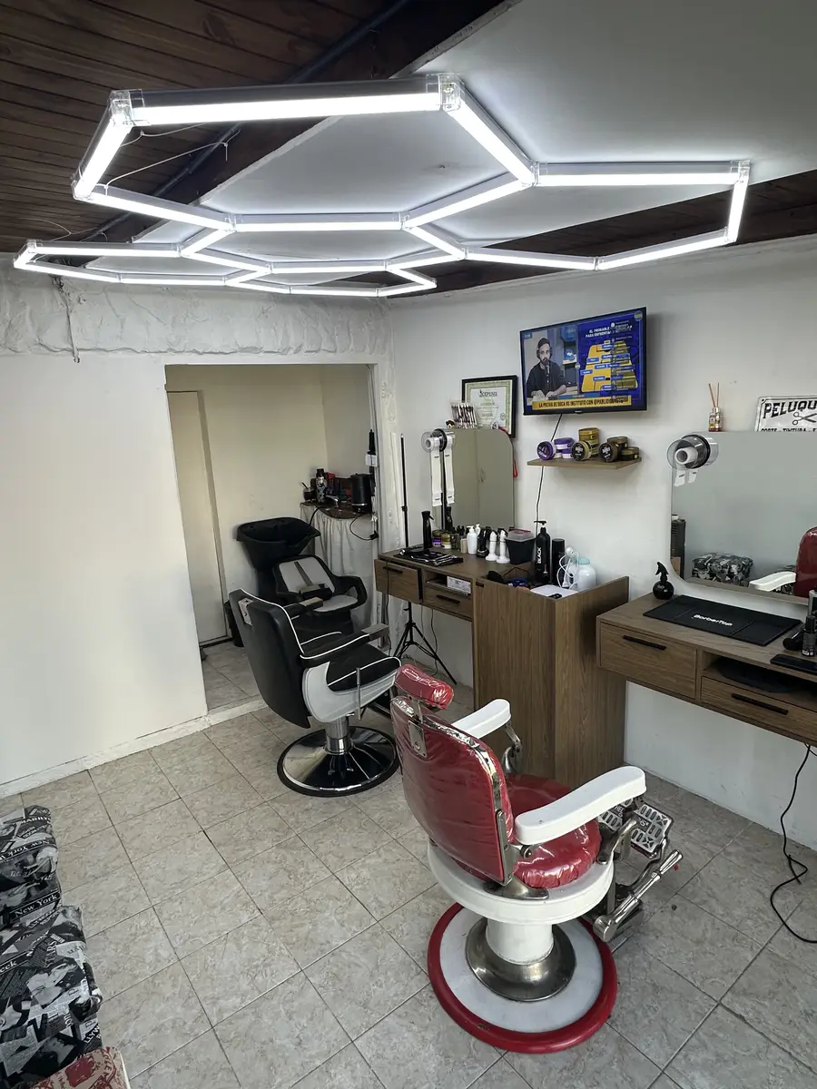 El local por dentro: sillones de barbero rojos y luces hexagonales